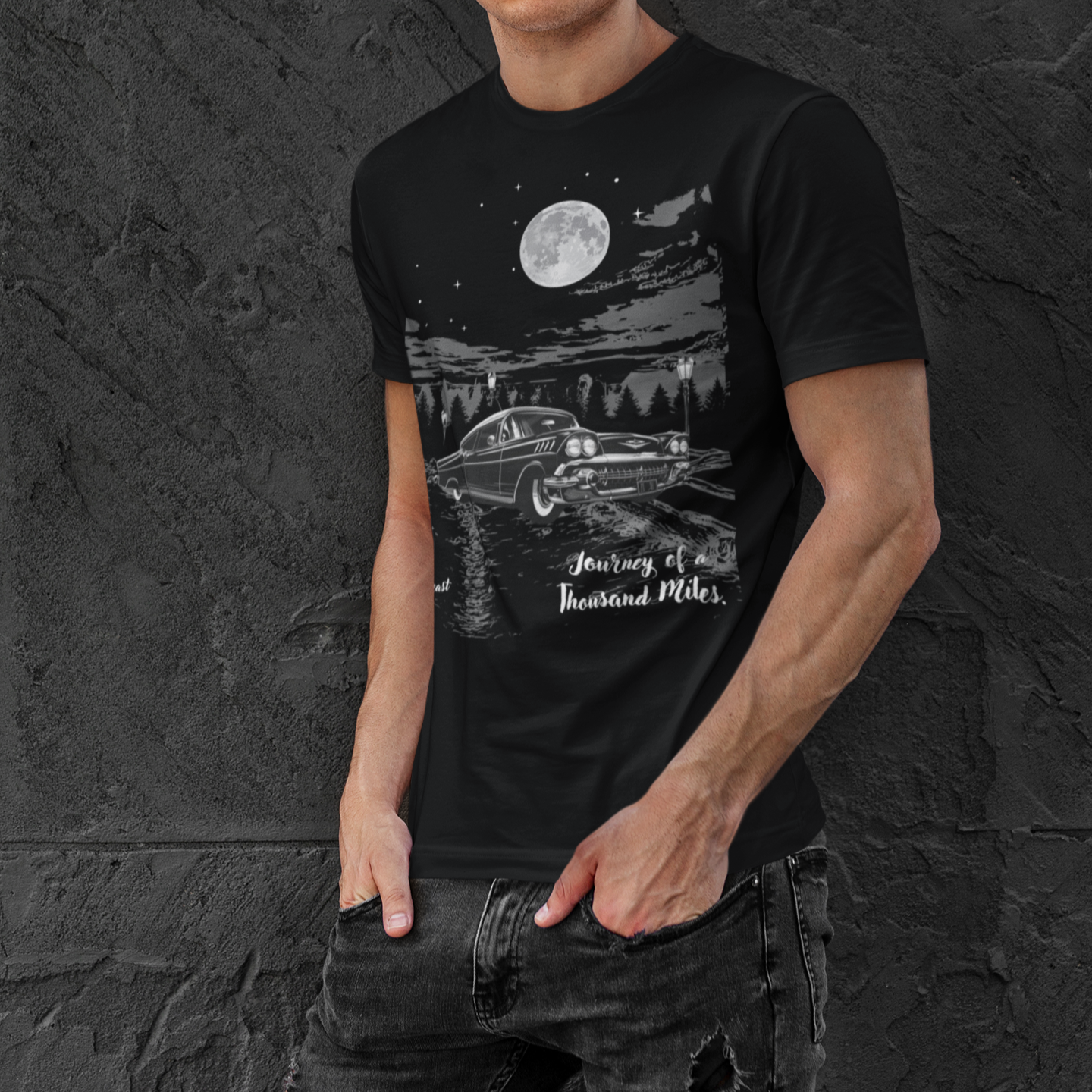 classic car enthusiast wearing a black t-shirt with a classic car graphic under a full moon, surrounded by trees and the phrase 'Journey of a Thousand Miles